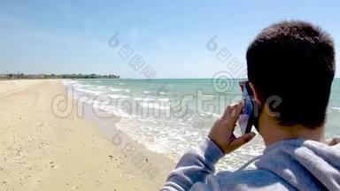 在希腊的哈尔<strong>基迪基</strong>，年轻人看着大海，用手机在沙滩上聊天